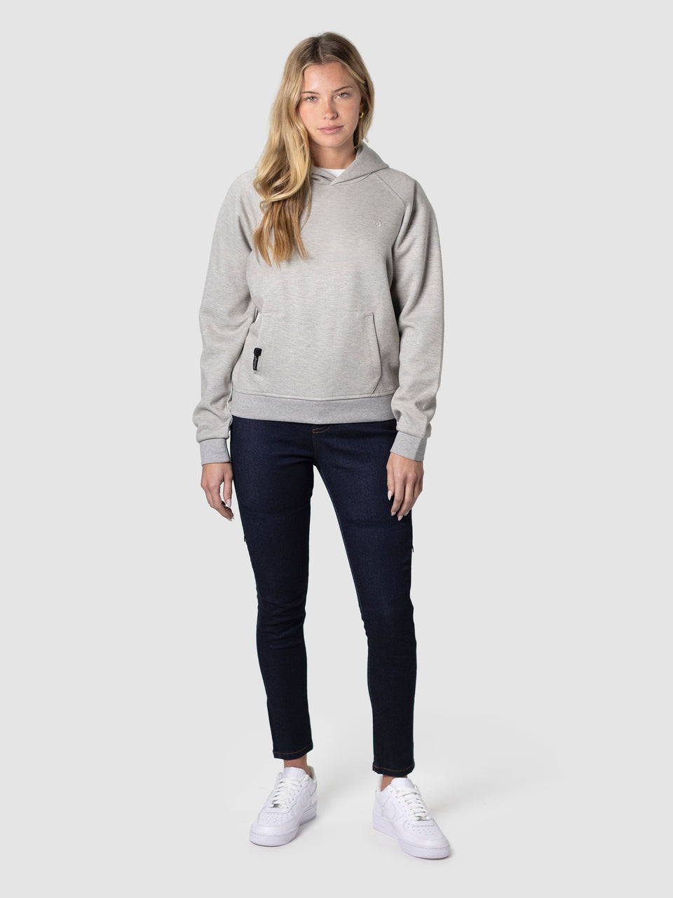 Woman in black trench coat with hoodie, jeans and sneakers